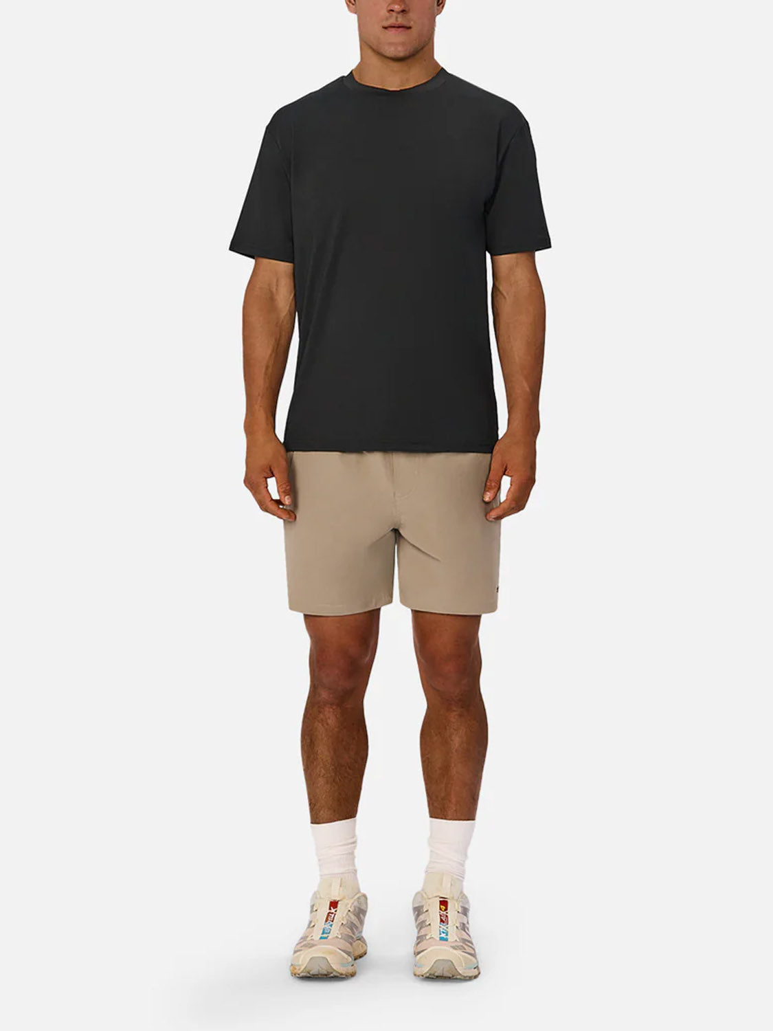 A man faces forward on a white background, wearing the Industrie Boldon T-Shirt in black, beige shorts, white crew socks, and white athletic sneakers.