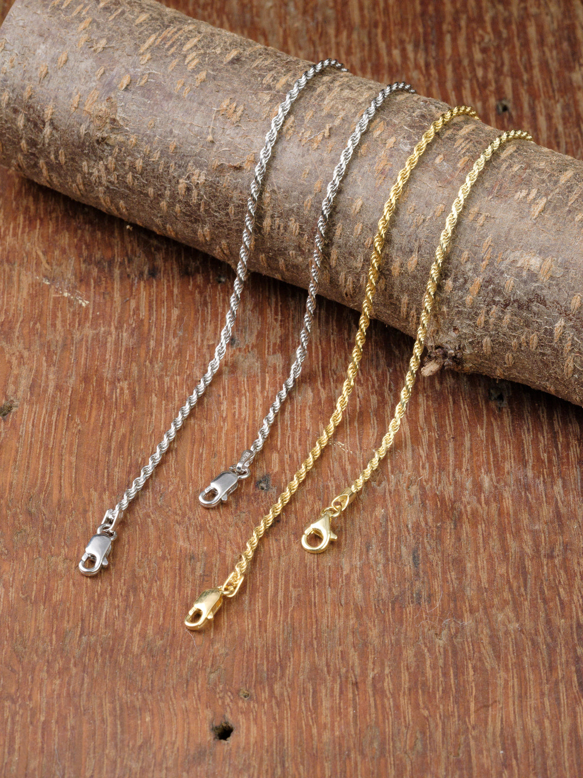 Two Orion 40 Bracelets by ID Menswear are elegantly displayed on a rustic wooden surface, draped over a textured log. Each handcrafted piece showcases Italian expertise and timeless design.