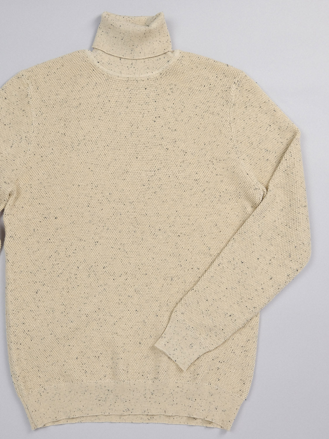 The Brampton High Neck Cotton Sweater by ID Menswear is showcased flat on a plain gray background, highlighting its beige speckled yarn, long sleeves, and high neck design.