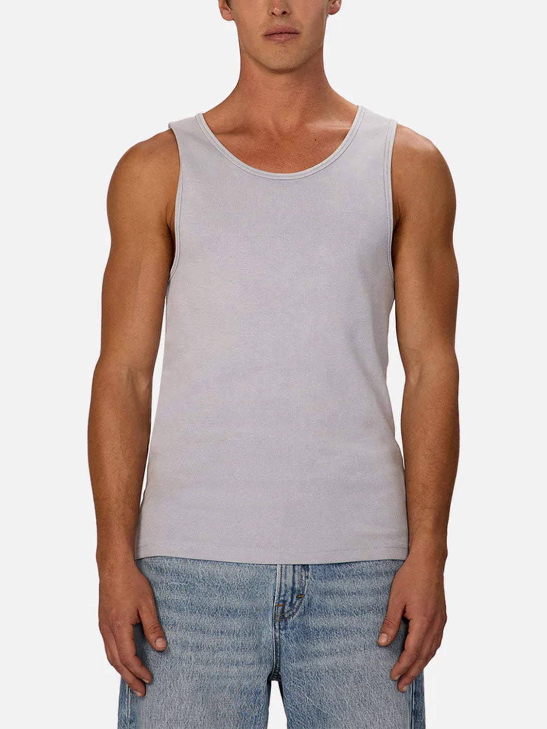 A man faces forward against a plain white background, showcasing the Industrie Washed Brando Ribbed Tank Top in light gray and light blue jeans—an effortless summer wardrobe staple.