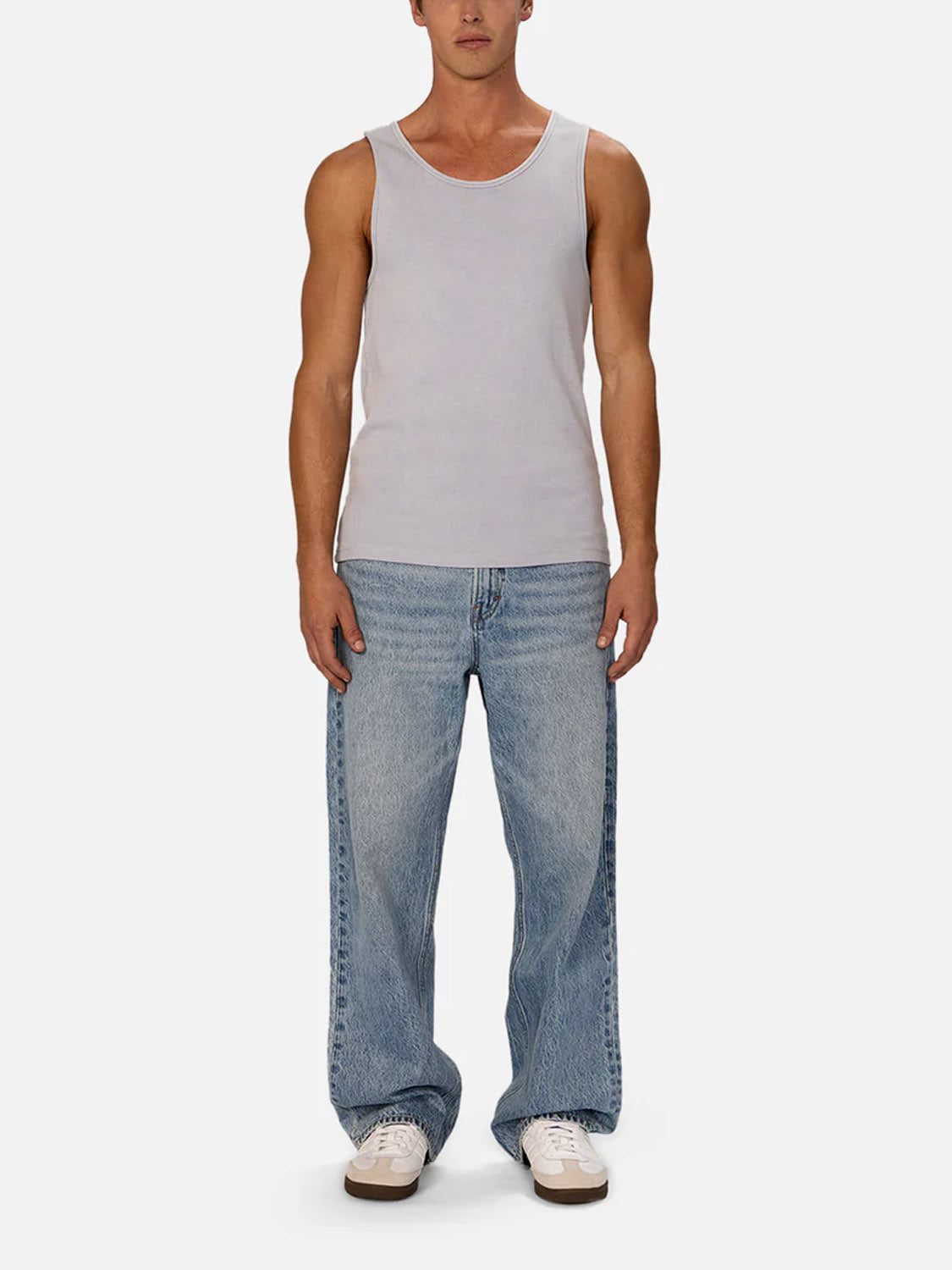 A person faces forward in the Industrie Washed Brando Ribbed Tank Top, loose light blue jeans, and white sneakers against a plain white background—a relaxed, summer-ready style.