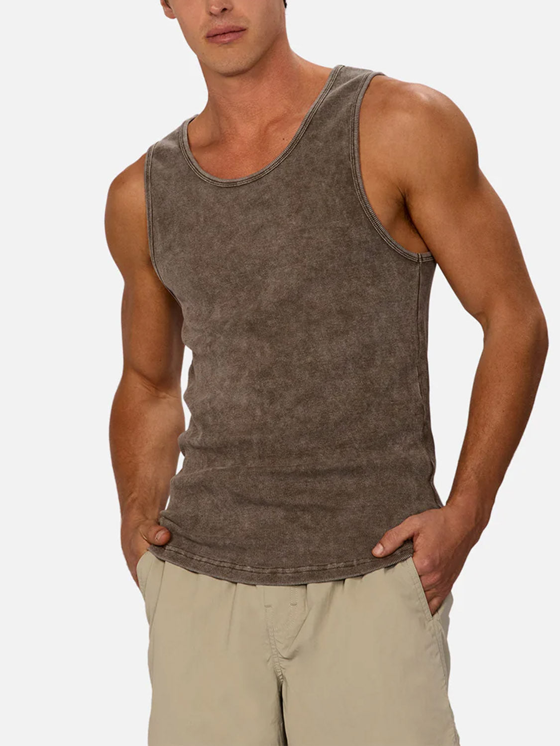 A man wears the Industrie Washed Brando Ribbed Tank Top and light beige shorts, standing with his hands in his pockets against a plain light background—a must-have summer style.