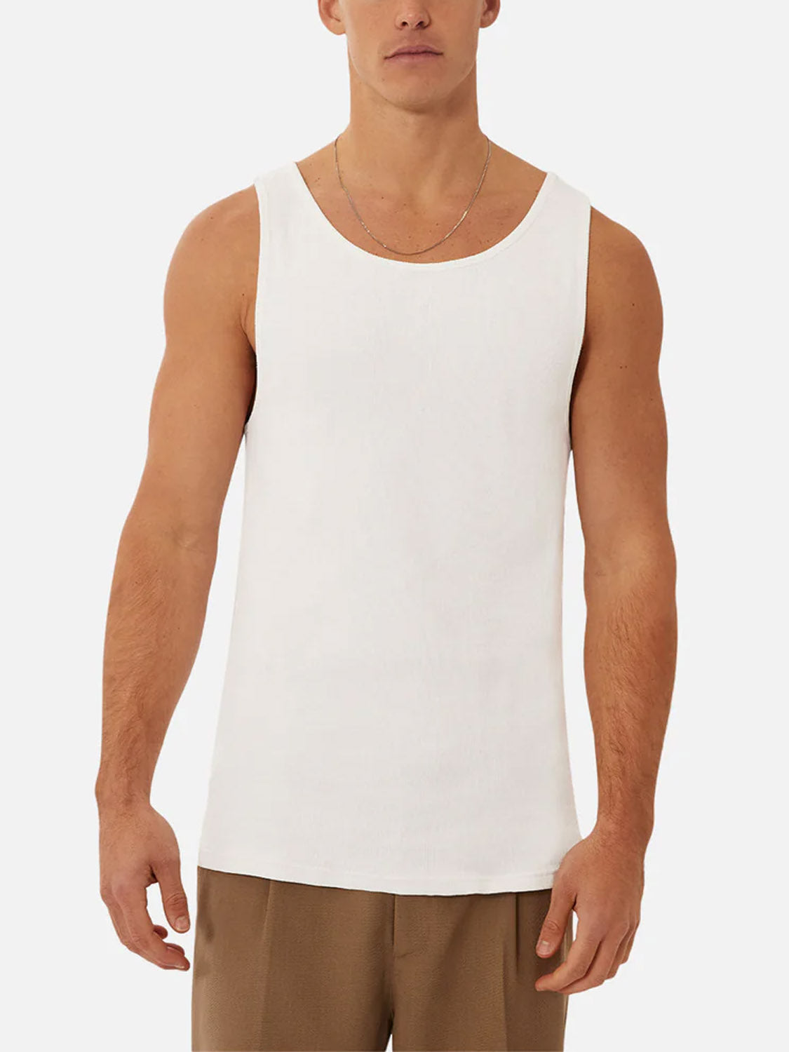 A man stands facing forward against a white background, wearing the Industrie Washed Brando Ribbed Tank Top in white and brown pants—an ideal addition to any summer wardrobe.
