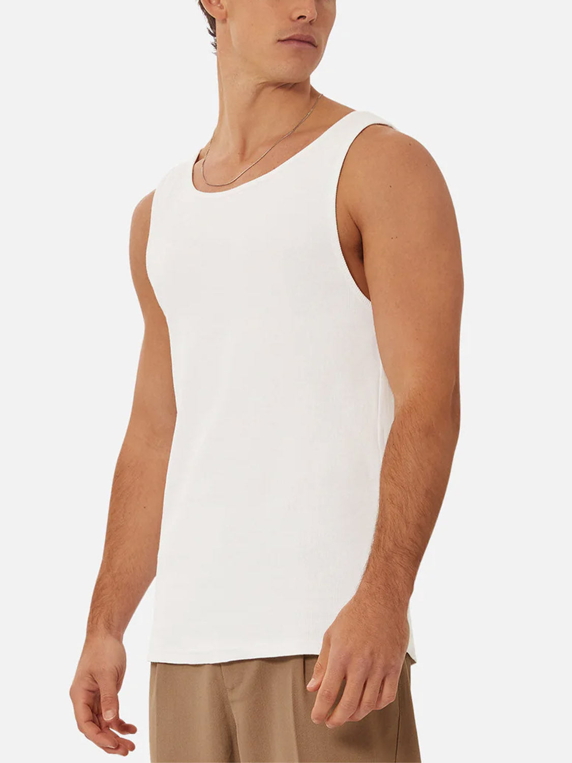 A man models the Industrie Washed Brando Ribbed Tank Top with light brown pants, standing against a plain white background and looking to his left.