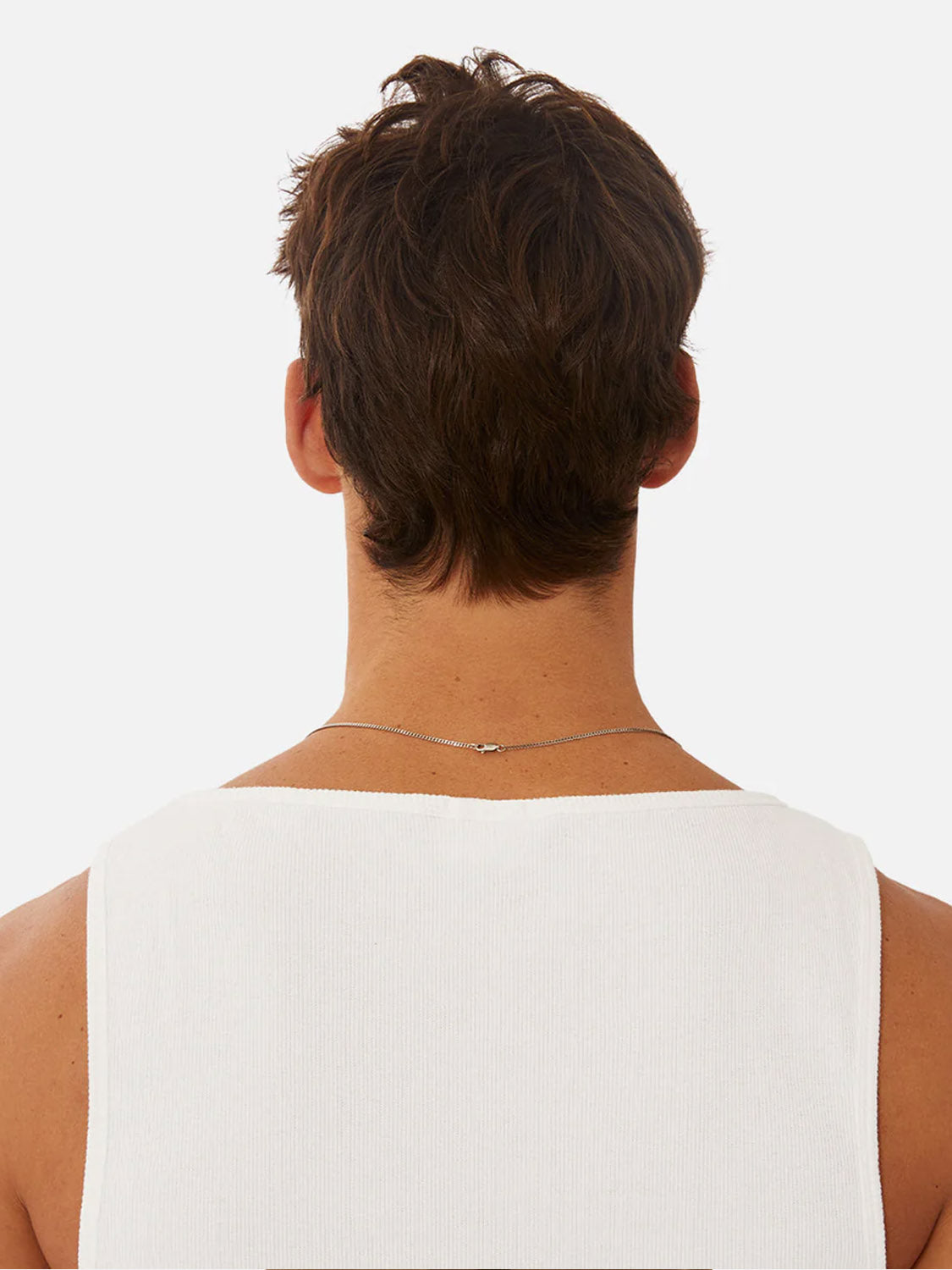 A person with short, tousled brown hair is shown from behind, wearing Industrie’s Washed Brando Ribbed Tank Top and a thin silver necklace—an effortless addition to any summer wardrobe—against a plain white background.