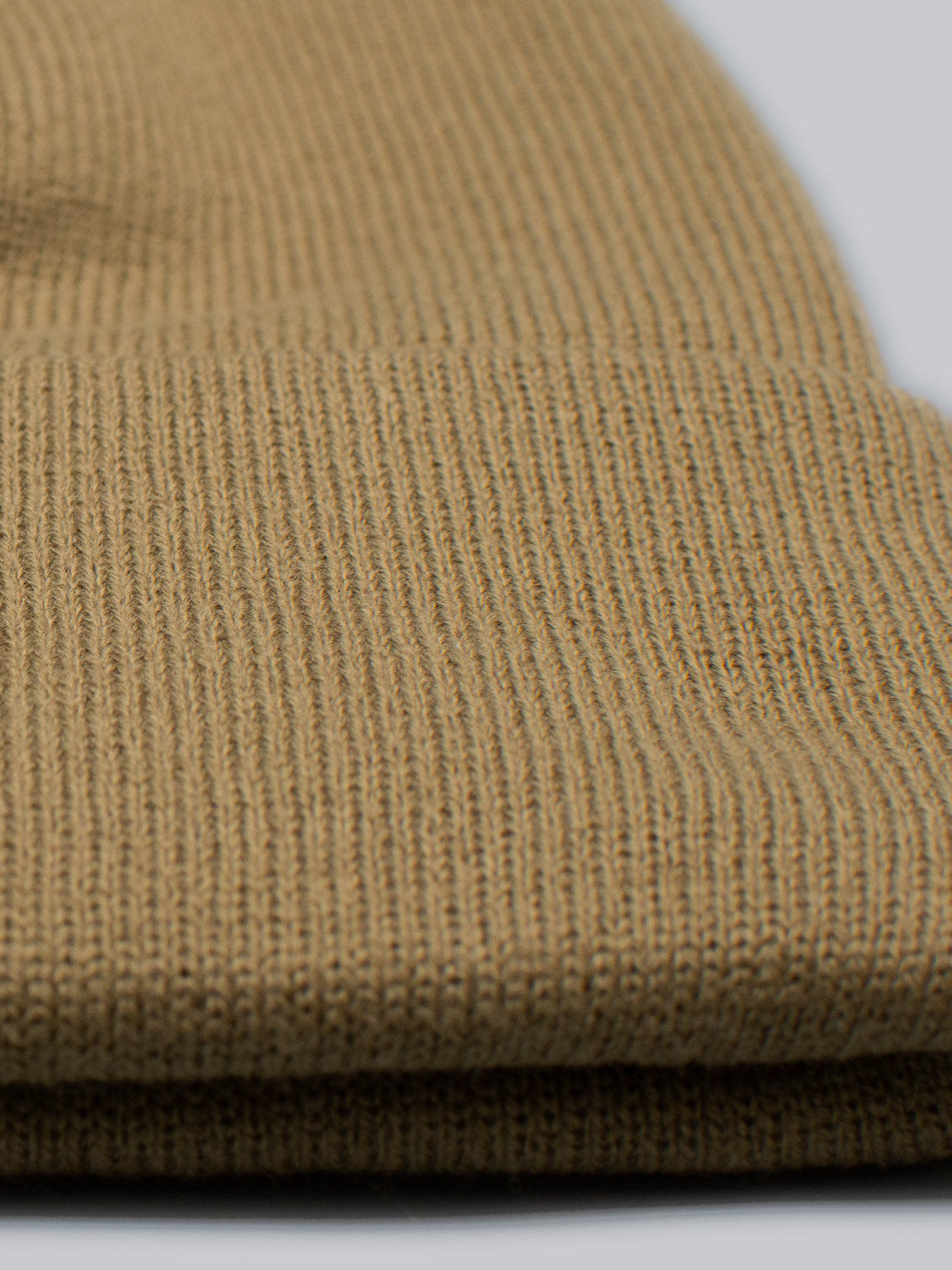 Close-up of the Bronx Acrylic Beanie by ID Menswear, highlighting its rich brown knitted fabric with a tight ribbed texture and woven pattern. The stretchable design ensures comfort, with the acrylic fabric slightly folded at the bottom.