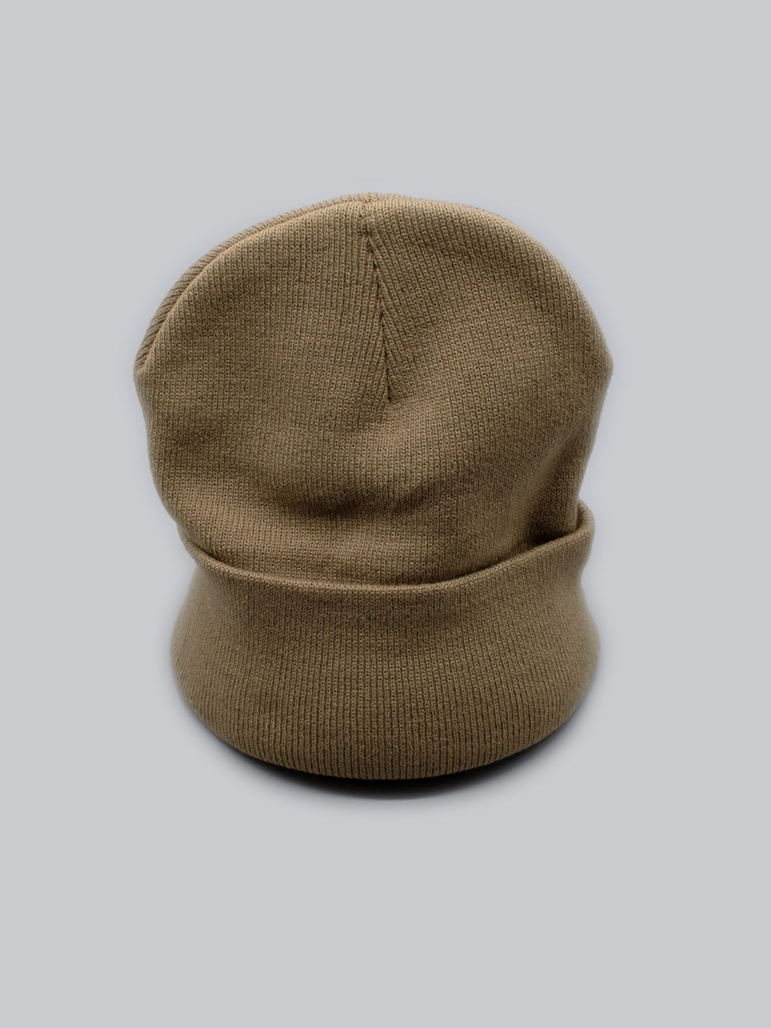 The ID Menswear Bronx Acrylic Beanie, with its brown knit and folded brim, is displayed against a light gray background. Its upright position highlights the textured stitching and stretchable design, offering both comfort and style.