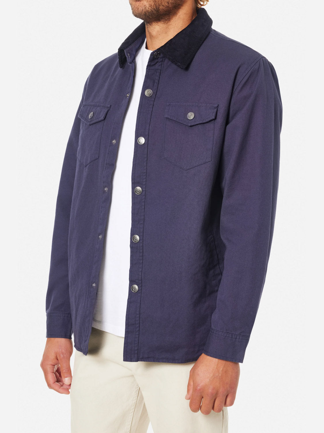 The person is wearing a Katin Campbell Jacket made of cotton canvas with a corduroy collar and two breast pockets over a white shirt, paired with light pants. The photo captures side and front views of the stylish ensemble.