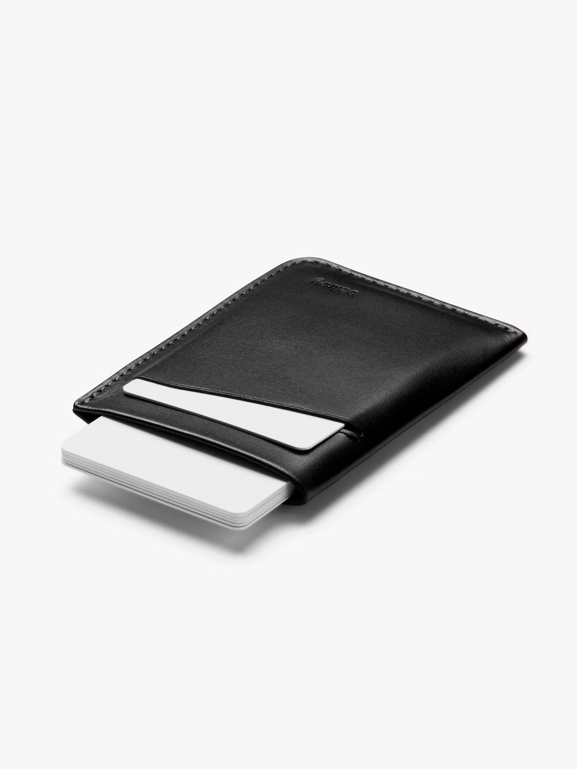 The Bellroy Card Sleeve Wallet, in black, features a slim minimalist design and holds white cards partly visible inside, displayed on a plain white background.