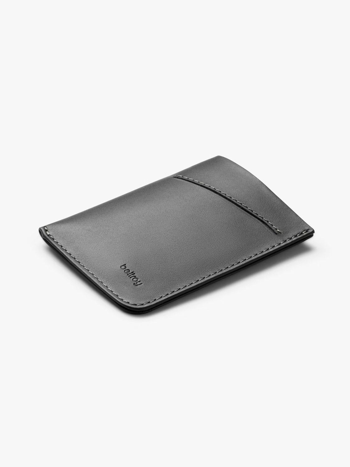 The Bellroy Card Sleeve Wallet is a slim, minimalist black leather holder with a curved front pocket, ideal for business cards. Displayed on a plain white background, “bellroy” is embossed near the lower left edge.