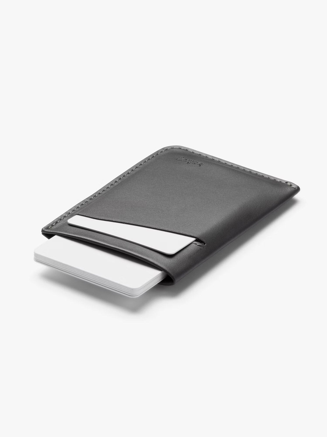 The Bellroy Card Sleeve Wallet is a slim, black leather card holder with visible stitching, holding a few white cards. This minimalist wallet appears against a plain white background.