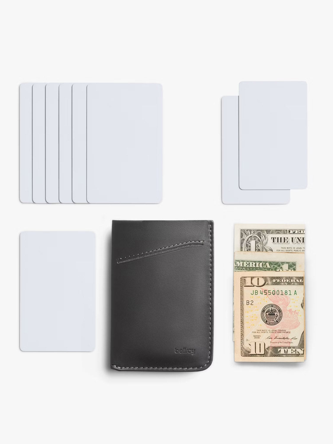 The Bellroy Card Sleeve Wallet in black is shown on a white background, surrounded by several white cards and a neatly stacked pile of folded U.S. dollar bills.