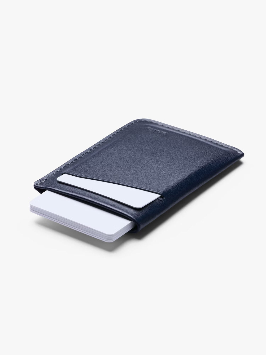 The Bellroy Card Sleeve Wallet, crafted in slim premium navy blue leather, features two visible card slots—each with a white card—set against a light gray background.