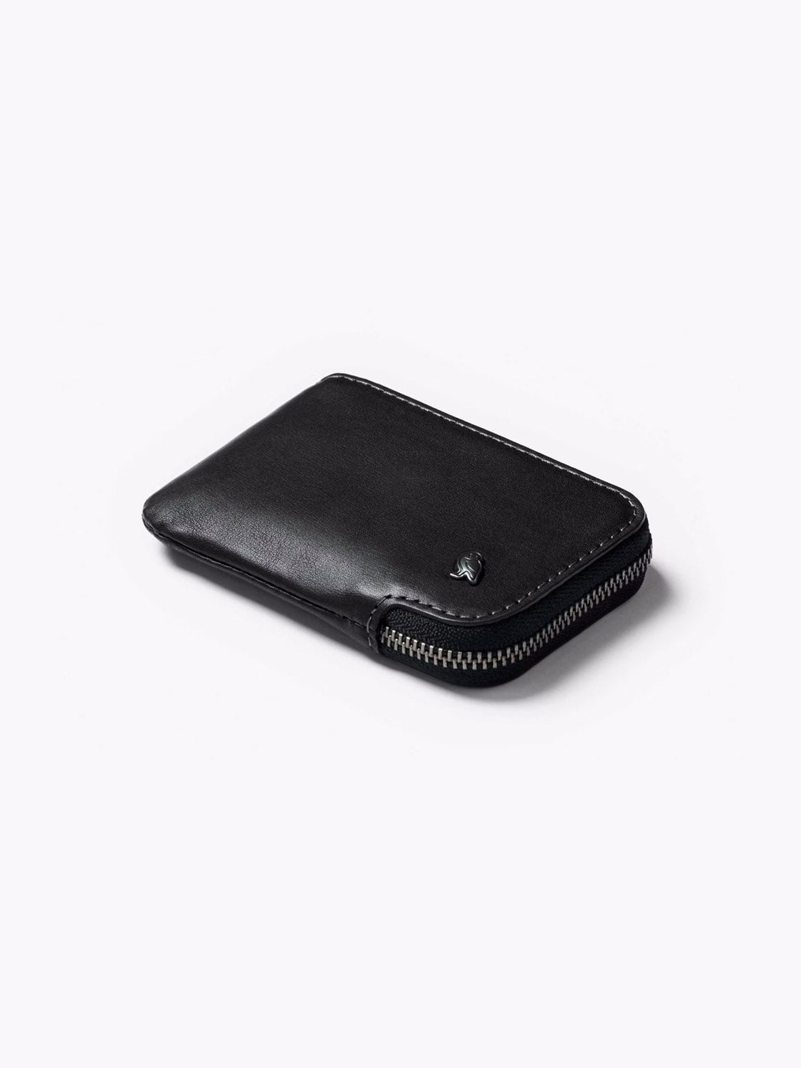 The Bellroy Card Pocket Wallet is a sleek black leather wallet with a zipper closure, shown closed and flat on a white background. A small metallic logo accents the corner, combining style and practicality for card storage.