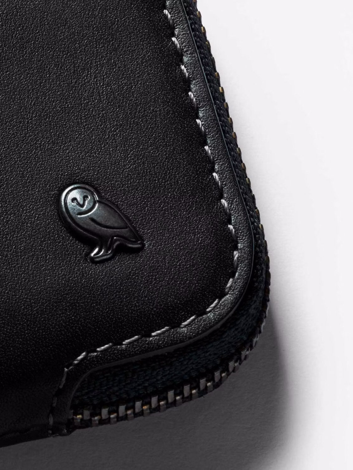 Close-up of the Bellroy Card Pocket Wallet in black leather, featuring an embossed owl logo and visible edge stitching.