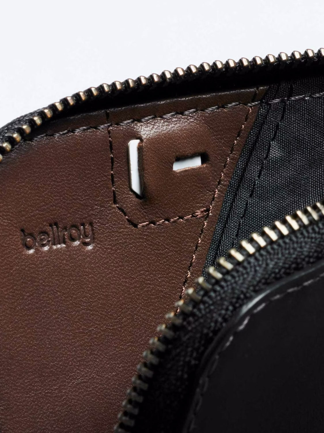 Close-up of the Bellroy Card Pocket Wallet’s interior in brown leather, featuring an embossed logo, visible zipper, fabric lining, and a card holder section.