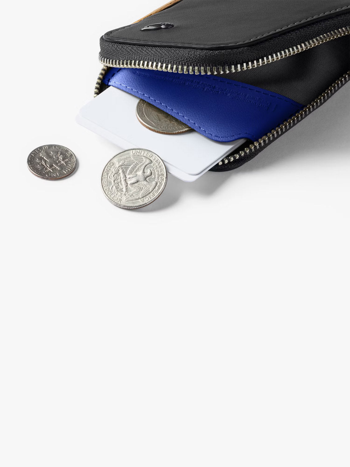 The Bellroy Card Pocket Wallet in black leather is partially open, displaying coins, a blue cardholder, and white cards inside, with some coins scattered on a white surface.
