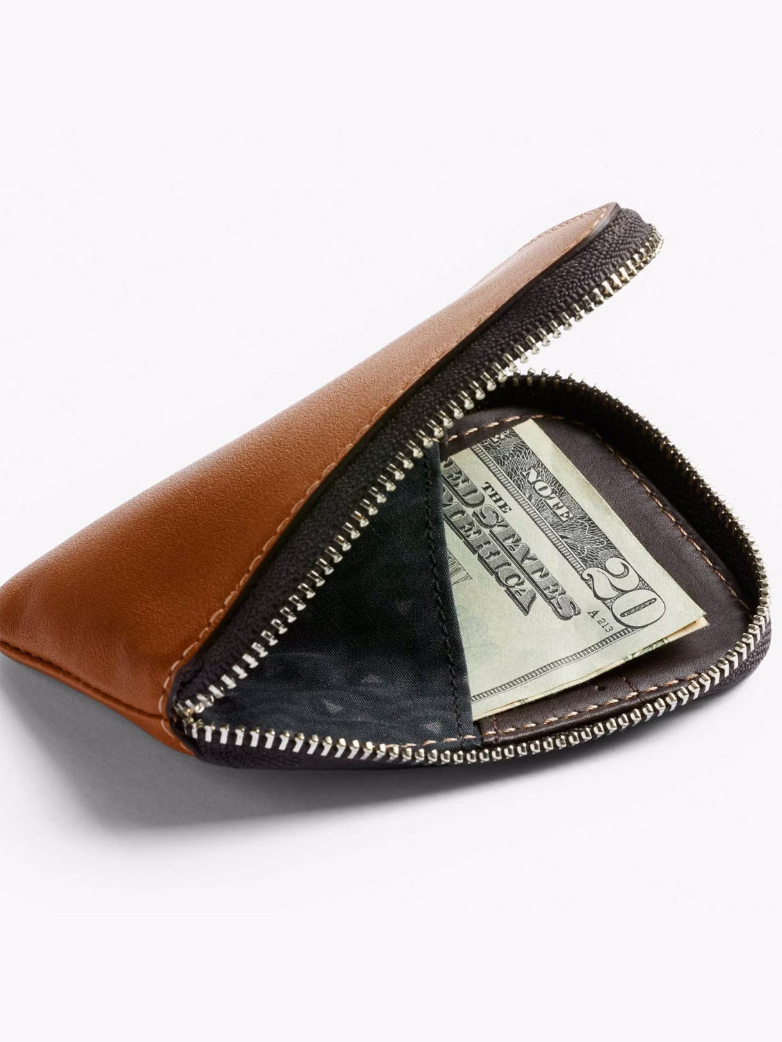 The Bellroy Card Pocket Wallet, a brown leather zippered card holder, is partially open to show folded U.S. twenty-dollar bills inside against a plain white background.