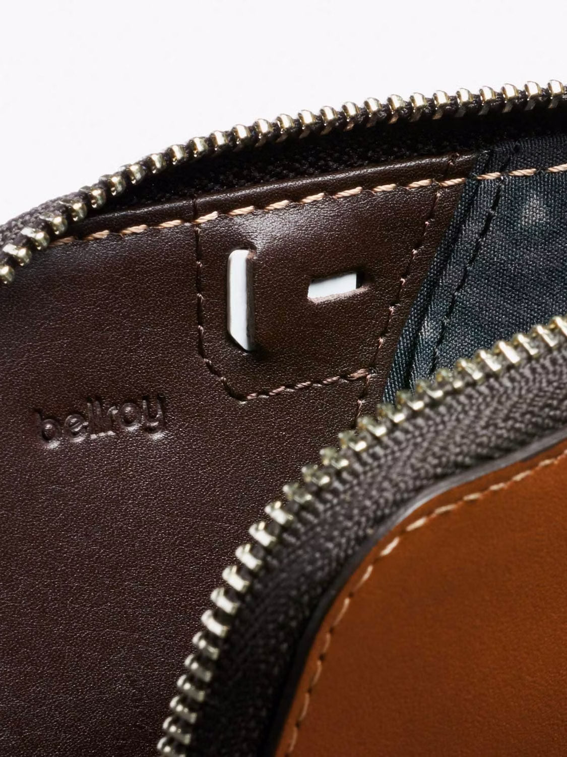 Close-up of Bellroy's Card Pocket Wallet in brown leather, featuring a zipper, detailed stitching, a small metal slot, and the debossed brand name inside, showcasing its stylish card holder design.