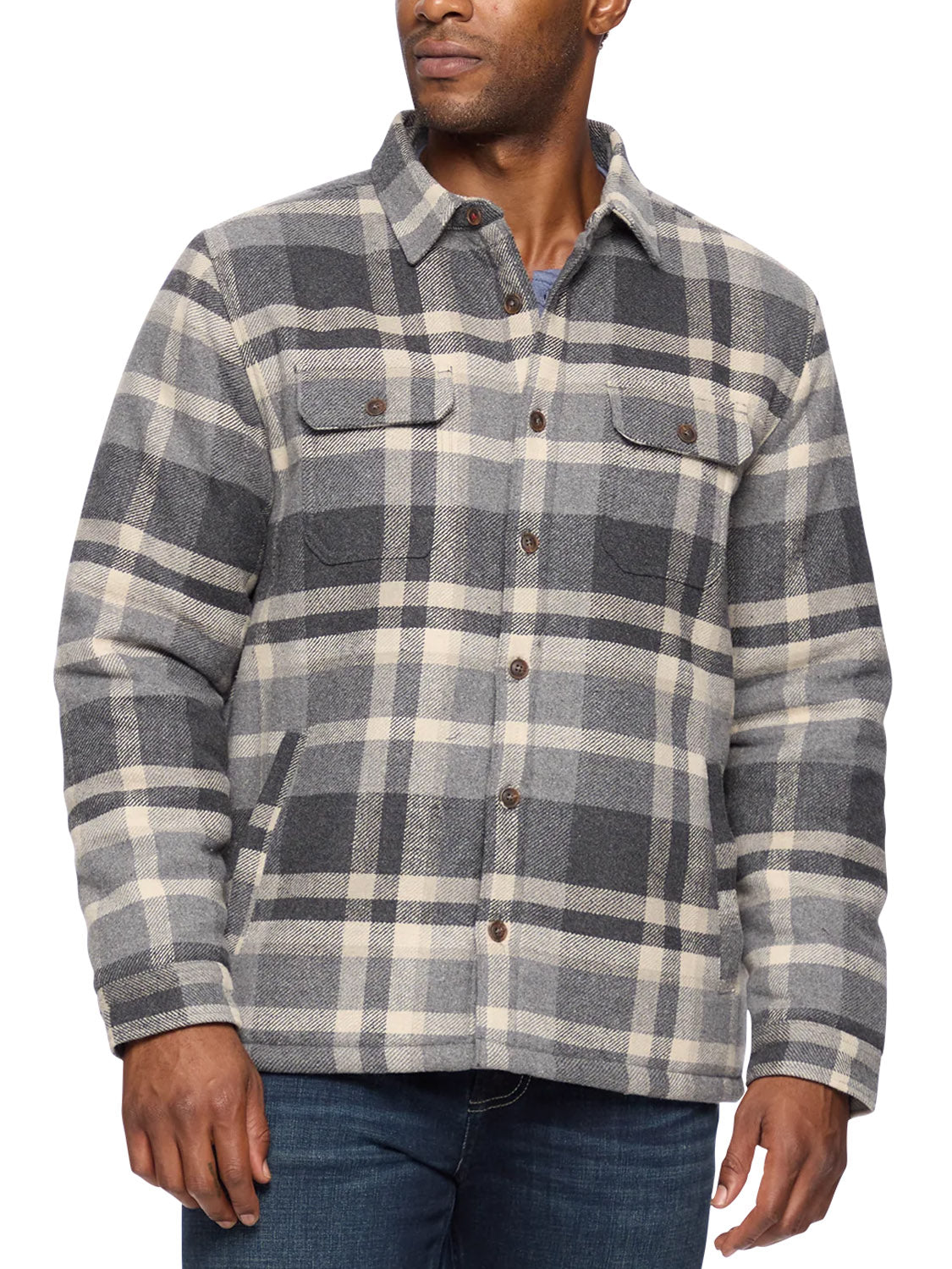 A man wears the Flag and Anthem Cassidy Sherpa Lined Shirt Jacket in gray and beige plaid with front pockets over a blue shirt and blue jeans, standing with one hand at his side and the other slightly bent.