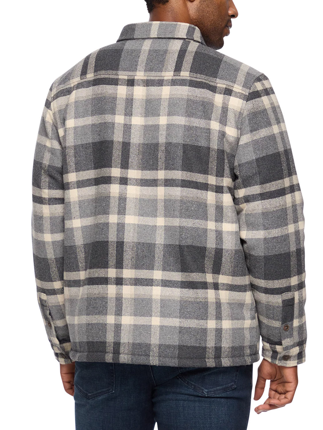 A man stands with his back to the camera, wearing the Flag and Anthem Cassidy Sherpa Lined Shirt Jacket in gray, black, and white plaid, paired with dark blue jeans.