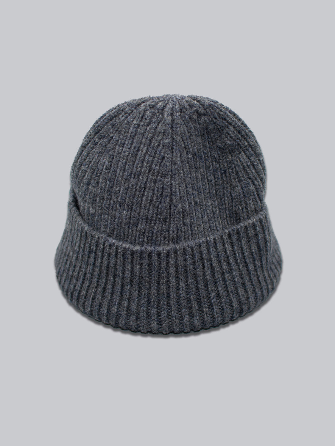 The Chamonix Wool Beanie by ID Menswear features a dark gray, ribbed texture crafted from 100% wool against a light gray background, delivering natural insulation.