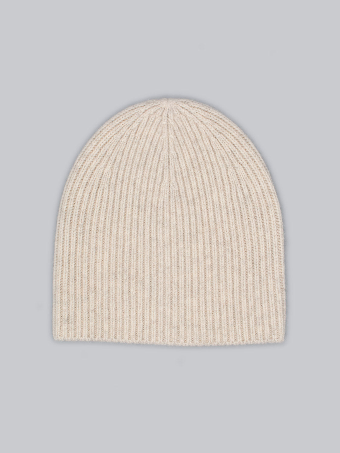 The ID Menswear Chamonix Wool Beanie, crafted from 100% wool, boasts a seamless rounded shape and natural insulation. Its beige ribbed knit design beautifully contrasts with the light gray background.