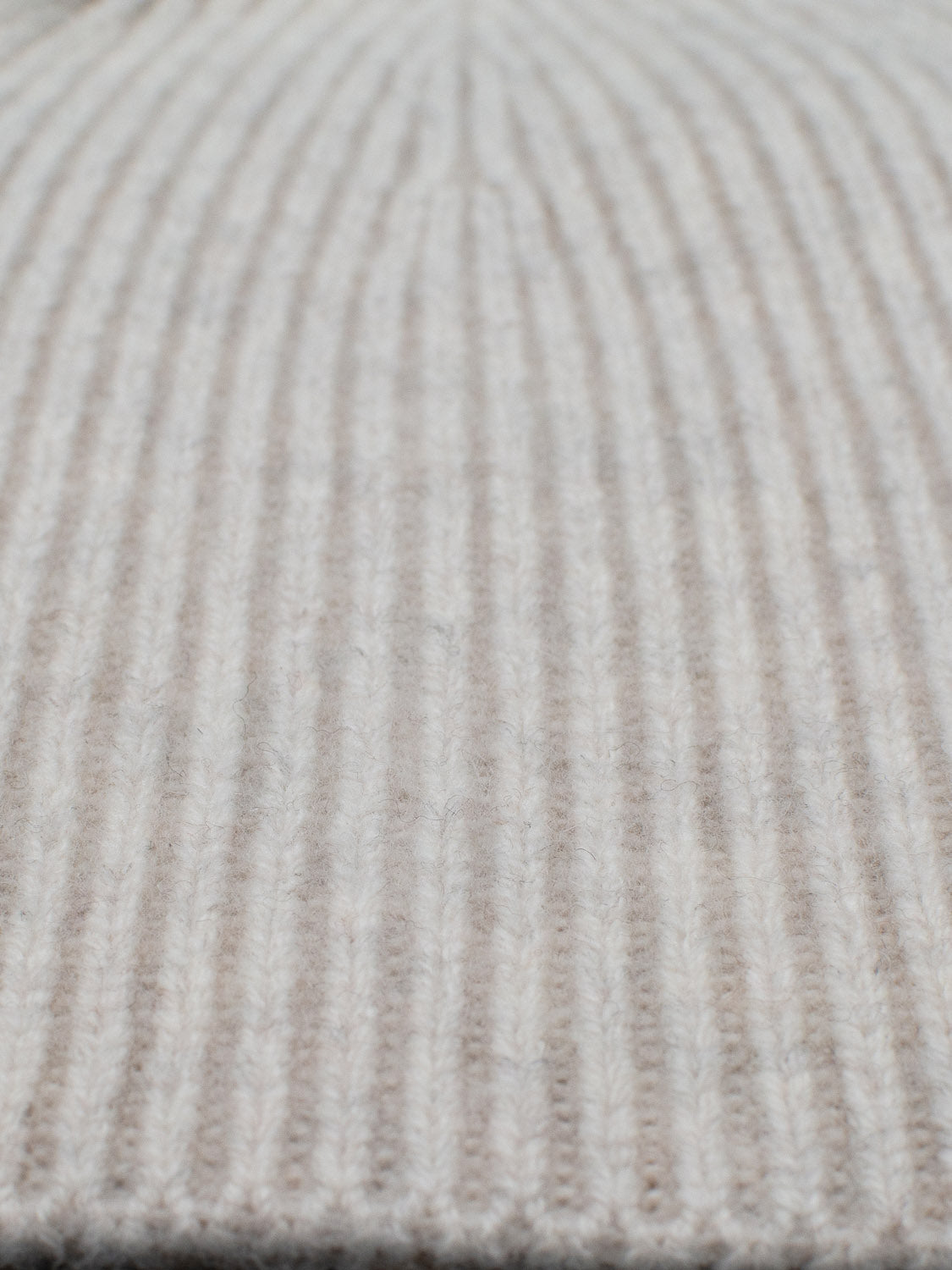 Close-up of a beige, ribbed texture knit fabric. The vertical rows create a pattern that gives natural insulation and a cozy look. Made from 100% wool, this soft material is ideal for crafting your own ID Menswear Chamonix Wool Beanie.