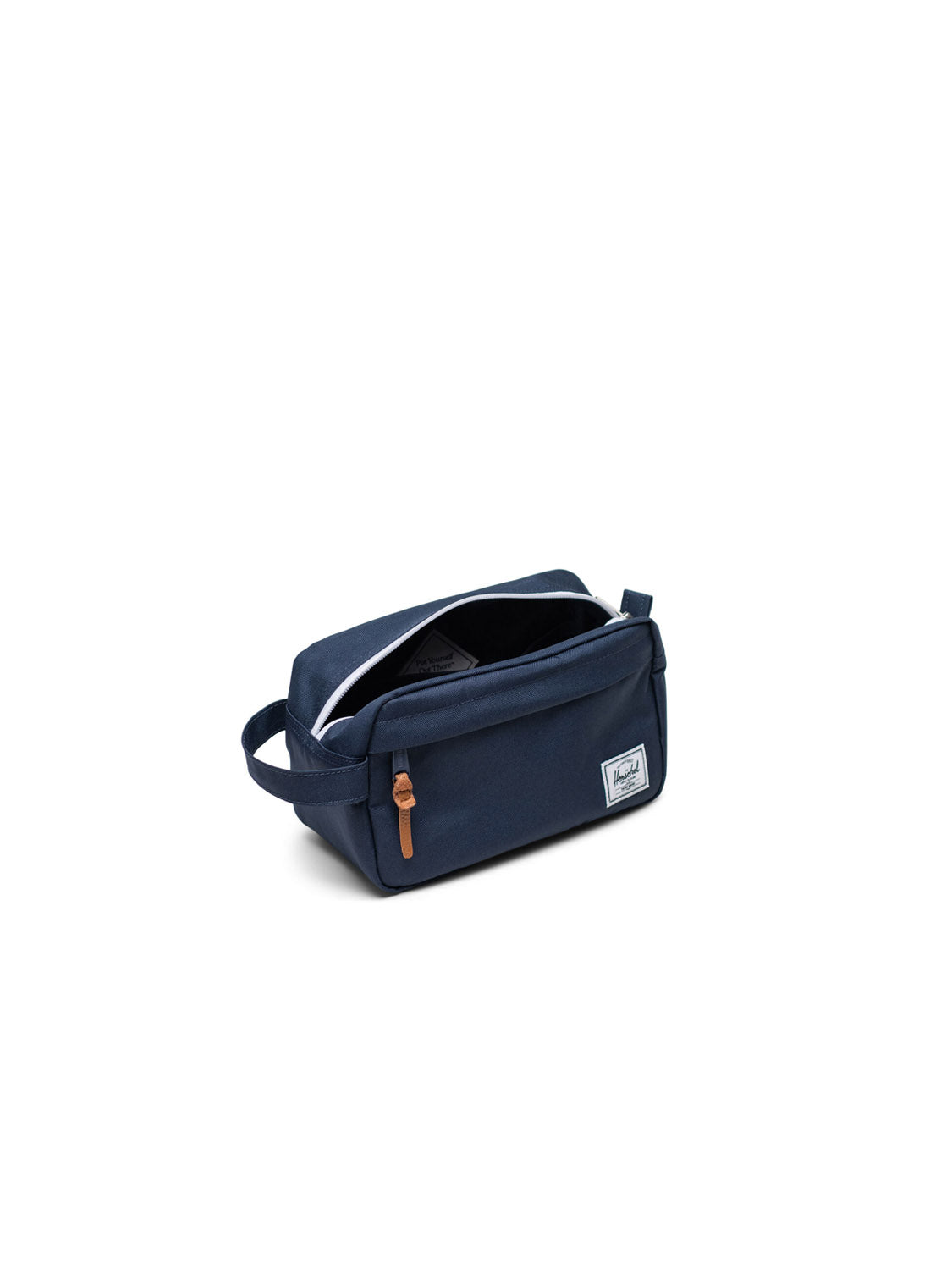 The Herschel Chapter Small Travel Kit is a navy blue rectangular toiletry bag with a side handle, front zipper pocket, white lining, brown zipper pull, and a small white rectangular Herschel brand patch on the front.
