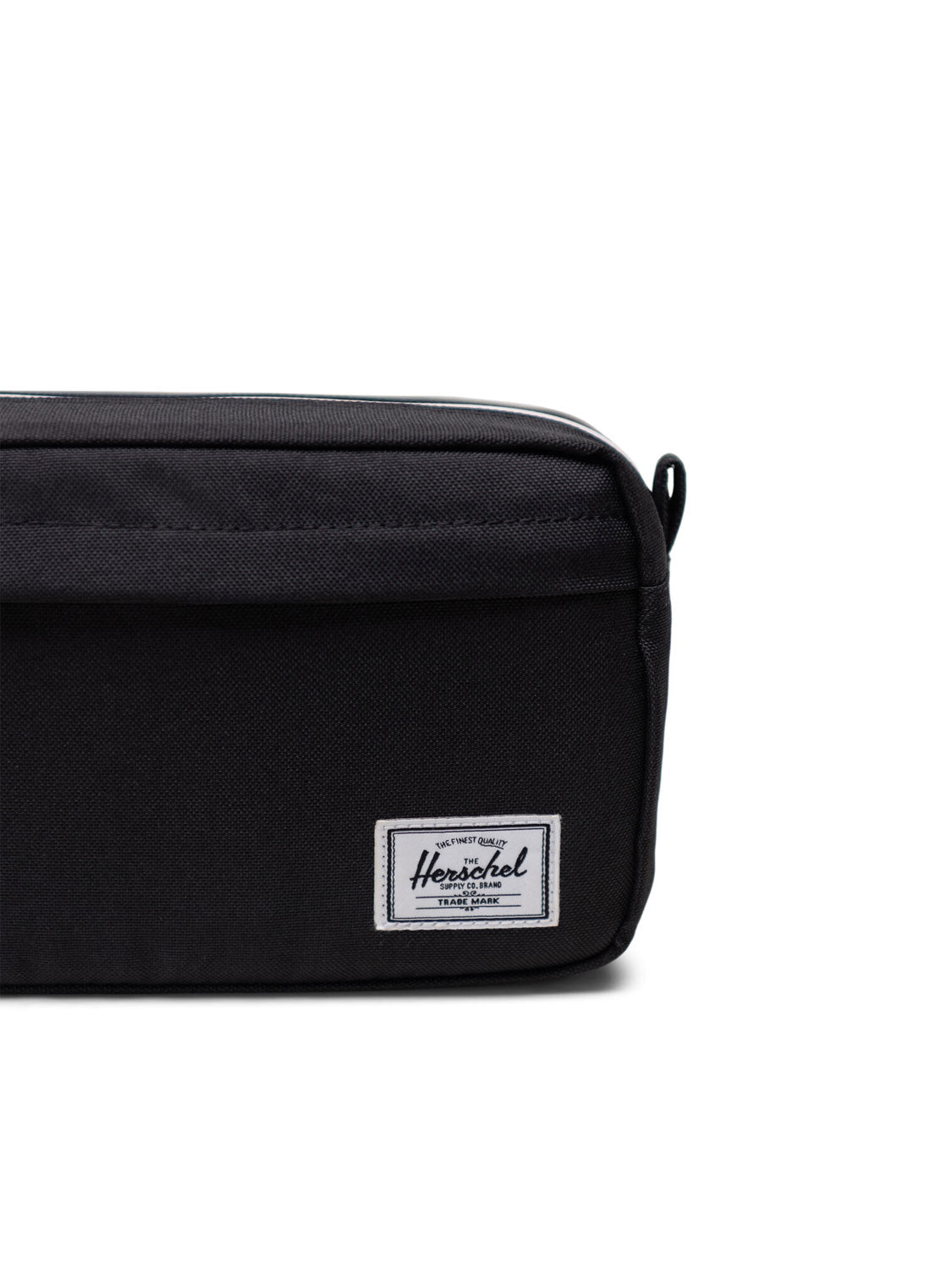 A close-up of the Herschel Chapter Small Travel Kit, a black toiletry bag featuring a white rectangular Herschel logo on the bottom right, durable fabric, and a zipper, making it a stylish and practical travel organizer.