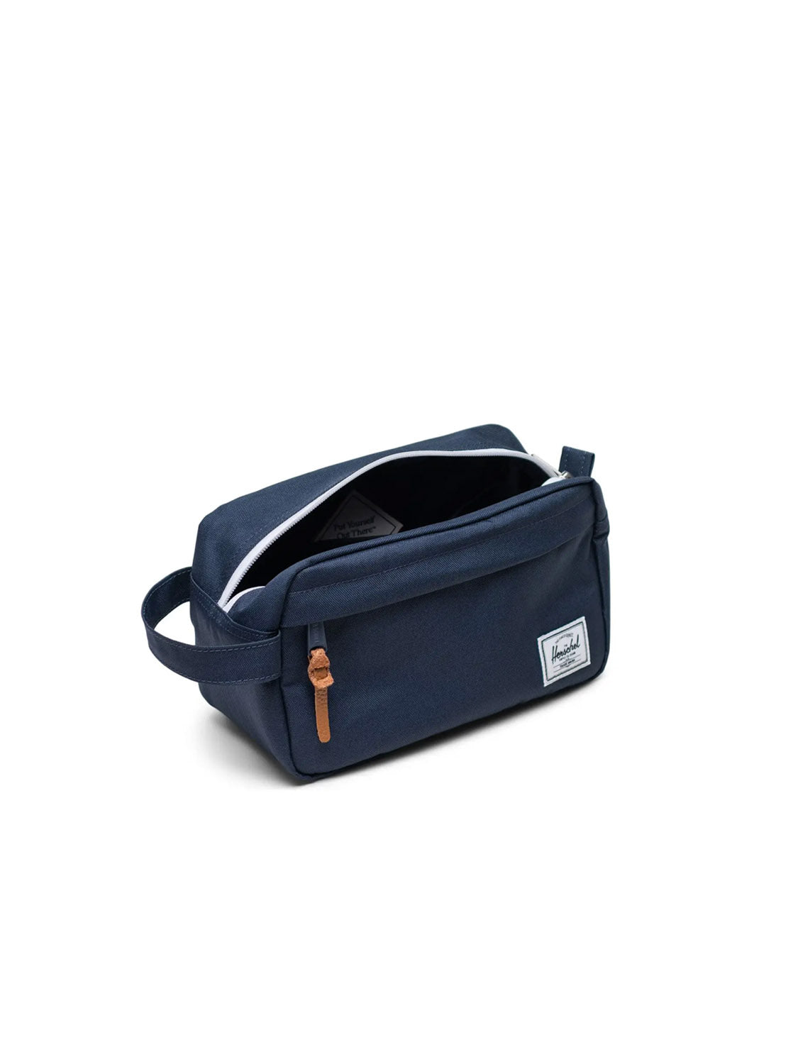 The Herschel Chapter Travel Kit is a navy blue toiletry bag with a waterproof zipper, brown leather pull, small side handle, and white rectangular brand patch—ideal as a sleek travel organizer.