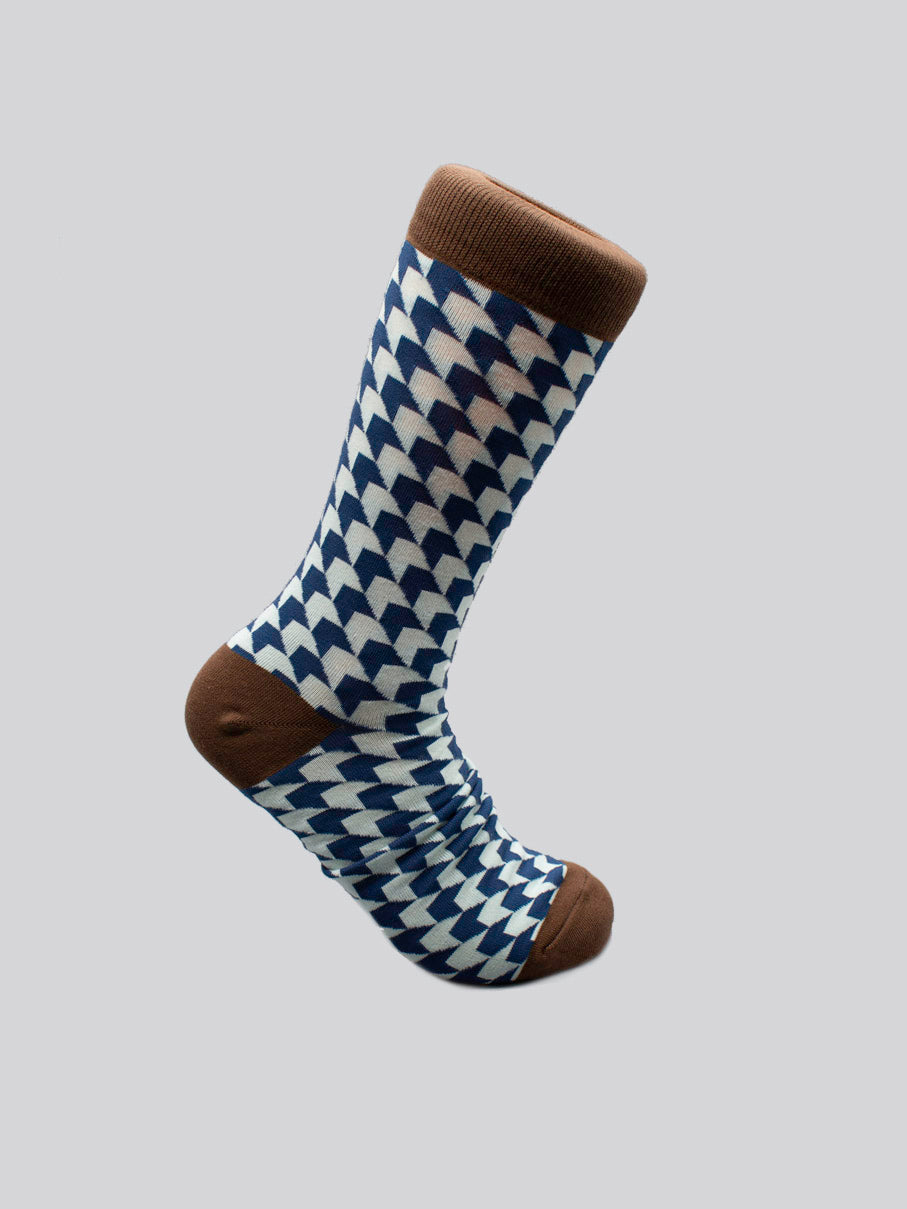 The Check Graphic Socks by ID Menswear are single socks with a blue and white houndstooth pattern, solid brown heel, toe, and cuff, in soft combed cotton. Designed for men’s shoe size 8-12, shown on a plain gray background.