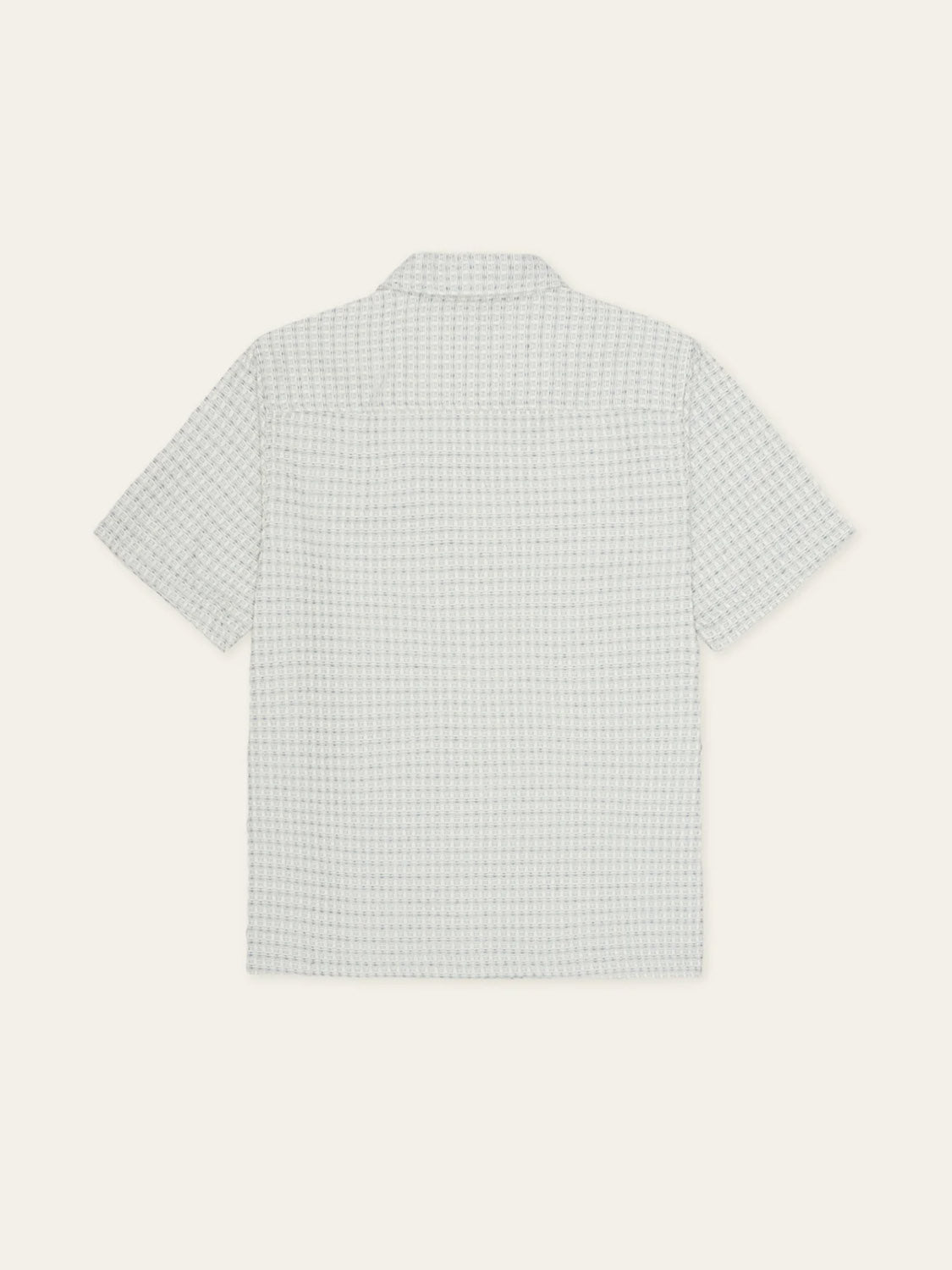The Les Deux Check Seersucker SS Shirt is a light grey, loose fit short-sleeve shirt with a subtle check pattern, displayed from the back against an off-white backdrop.