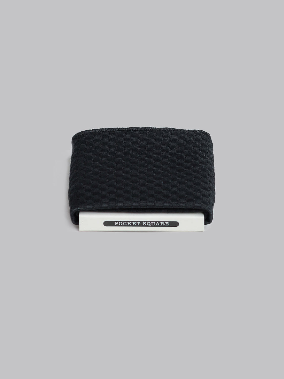 A folded black textured Chicago Pocket Square by ID Menswear, handmade in Brooklyn from 100% cotton, is clipped with a silver holder labeled POCKET SQUARE against a plain gray background.