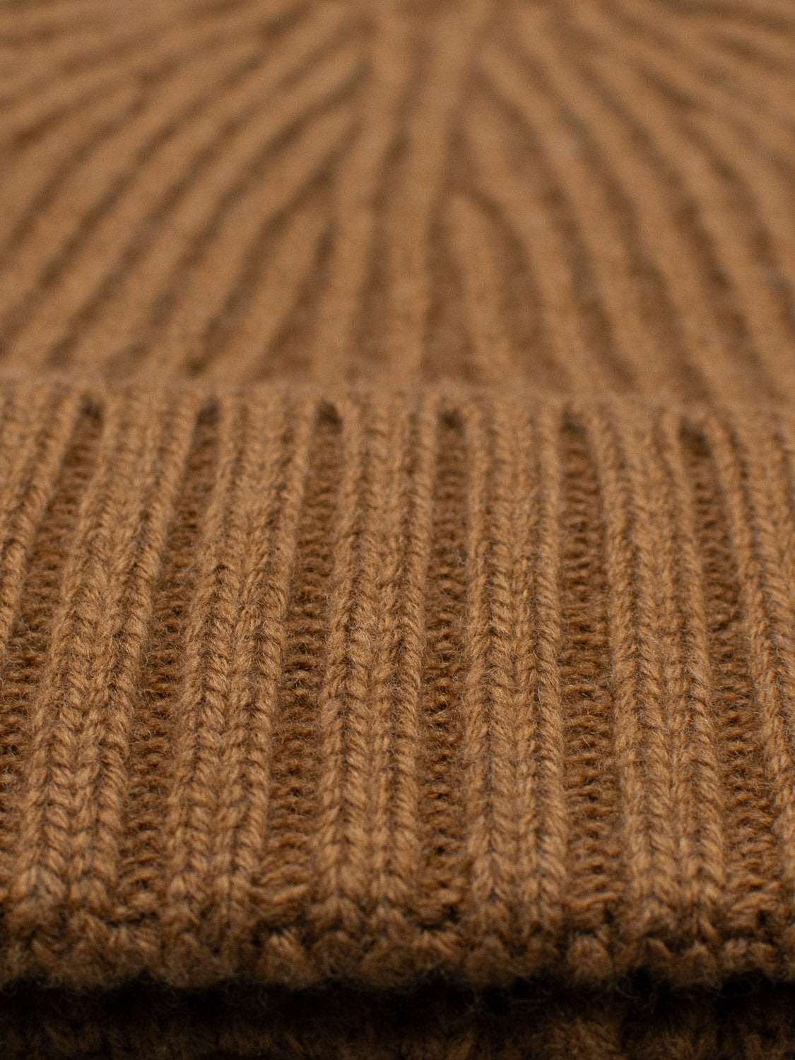 Close-up of the Cho Oyu Merino Wool Fishermans Beanie by ID Menswear, highlighting the brown ribbed knit fabrics detailed texture. Made from soft merino wool, its ideal for warm winter accessories, with a focus on its intricate stitch patterns.