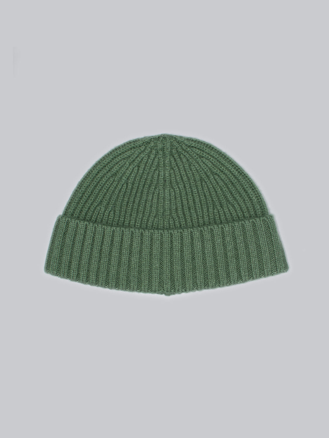 The ID Menswear Cho Oyu Merino Wool Fishermans Beanie, featuring a ribbed pattern and folded brim, is set against a light blue background, making it an ideal winter wardrobe addition.
