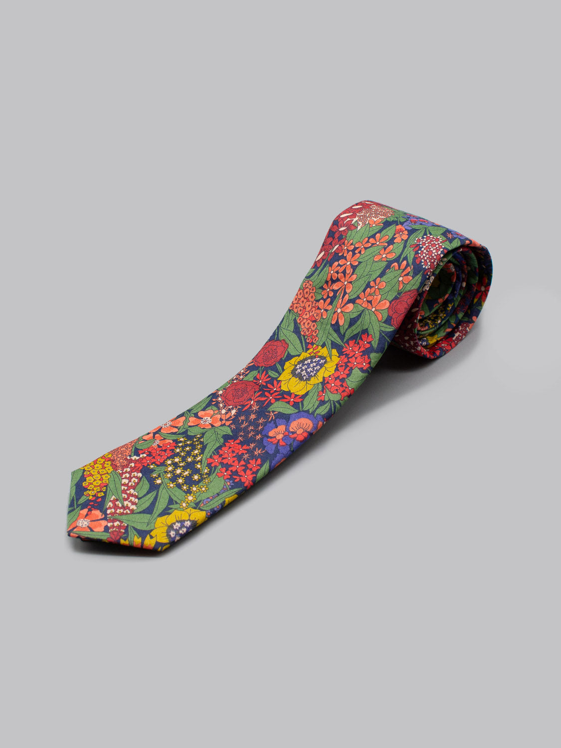 The Liberty of London Tana Lawn™ Ciara Tie by ID Menswear is handmade in Brooklyn, featuring a vibrant multicolored floral pattern on a light gray background.
