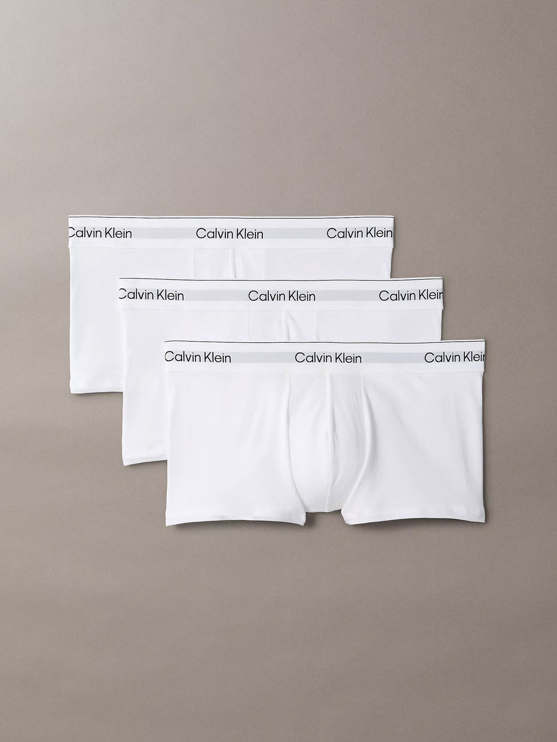 Three pairs of Calvin Klein NB4389 Icon Cotton Stretch 3-Pack Low Rise Trunks are laid flat in a staggered stack. Each features a stitch-free waistband with the Calvin Klein logo in black for enhanced comfort.