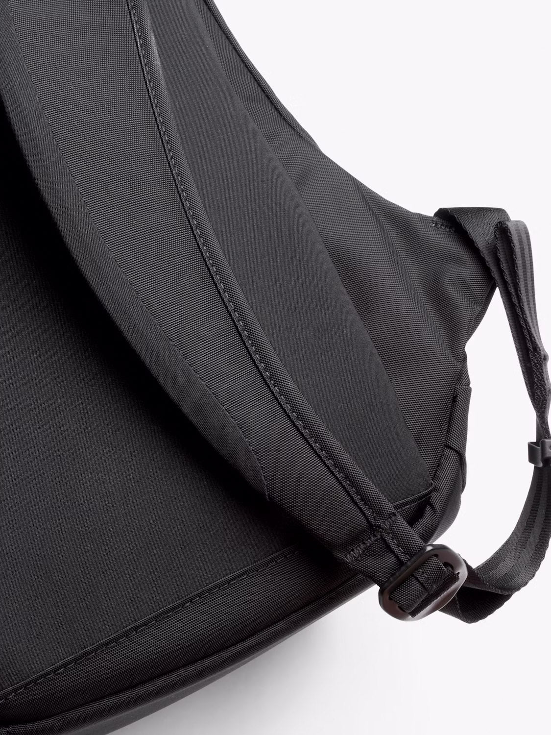 Close-up of the Bellroy Classic Compact Backpack - 16L in black, made from durable recycled fabric with adjustable padded shoulder straps, shown against a light background.