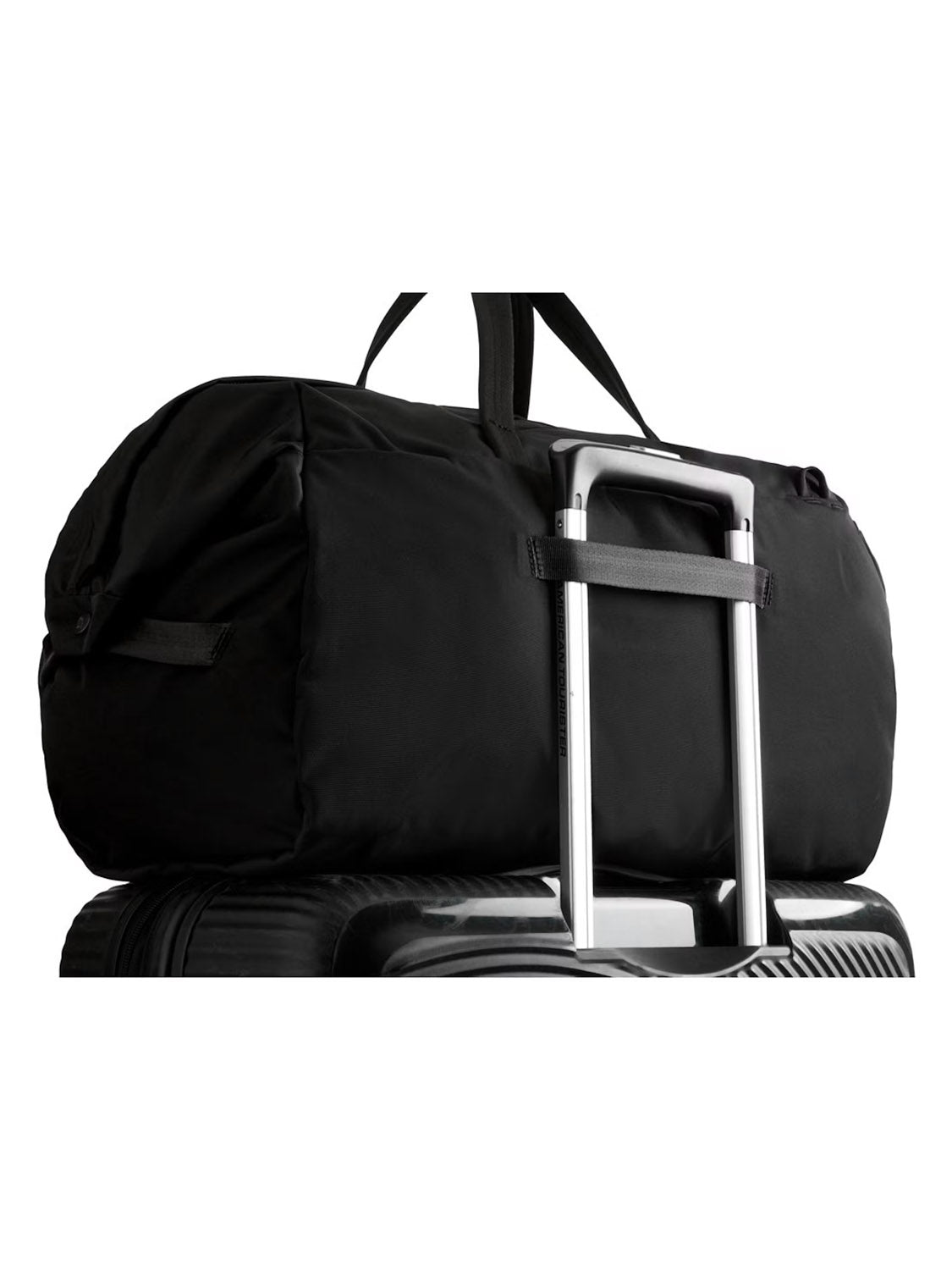 The Bellroy Classic Weekender Duffle Bag - 45L in black, featuring a luggage pass-through, is set atop the handle of a hard-shell suitcase, both displayed against a white background.