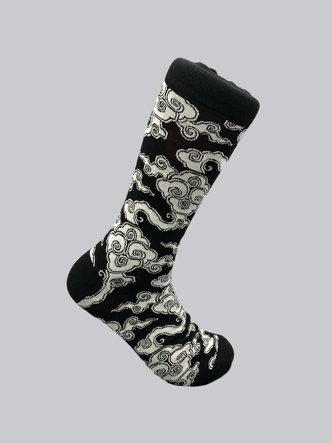 The Cloud Graphic Socks by ID Menswear feature a single black sock crafted from breathable combed cotton, adorned with a white swirling cloud pattern on a plain gray background.