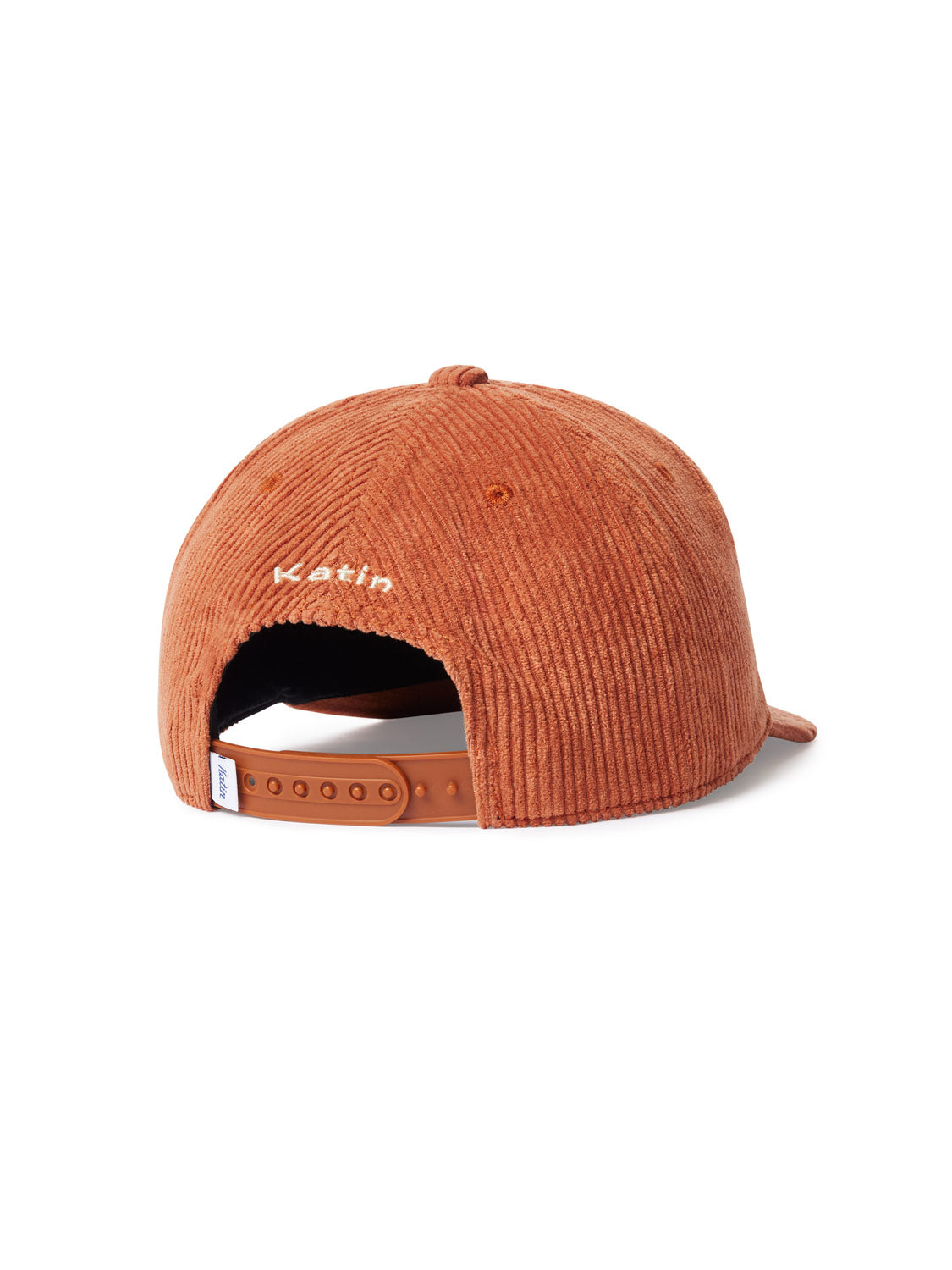 The Katin Cortex Hat is a rust-colored cotton corduroy hat featuring an adjustable brown plastic strap at the back and small white embroidered text above the opening.