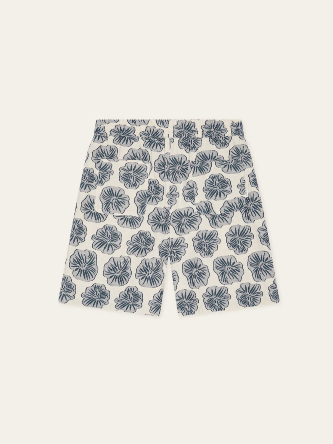 Back view of Les Deux Dahlia Jacquard Shorts in white cotton blend with bold dark blue floral print, featuring two back pockets. Displayed on a plain light background.