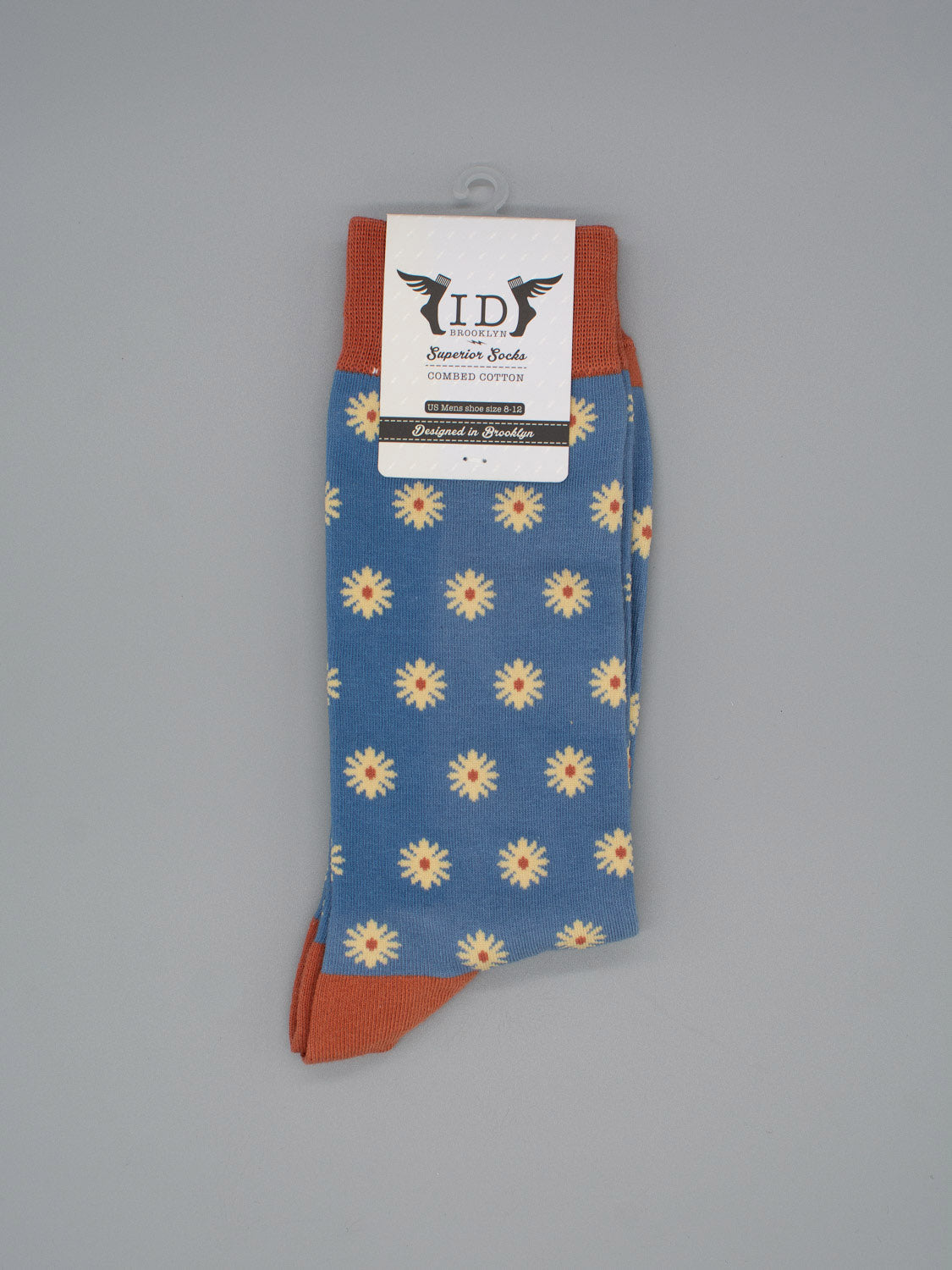 Dazed Graphic Socks by ID Menswear feature a daisy pattern with rust cuffs, heels, and toes on high-quality combed cotton—perfect for any modern wardrobe. Shown on a plain gray background with an ID Superior Socks label.