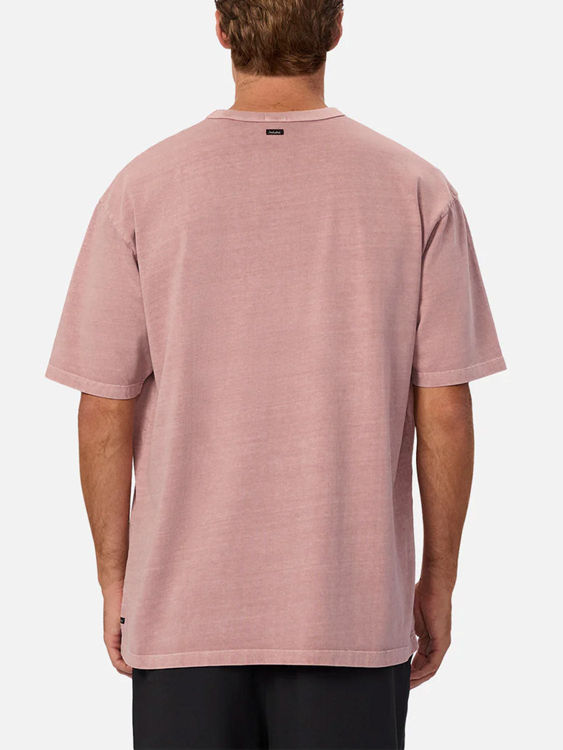 A man is seen from behind wearing Industrie’s The Del Sur Tee, a relaxed-fit 100% cotton crew neck in dusty pink, paired with black shorts, set against a plain white background.