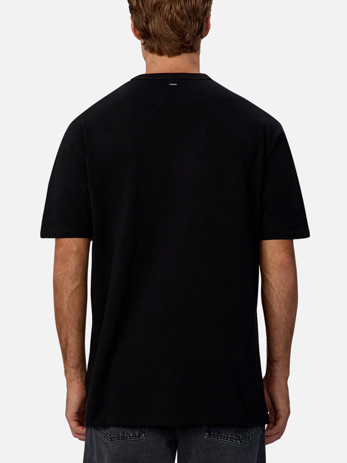 A person with short brown hair is seen from behind wearing Industrie’s The Del Sur Tee, a plain black crew neck t-shirt, and dark jeans against a light grey background. The relaxed fit offers everyday comfort and style.