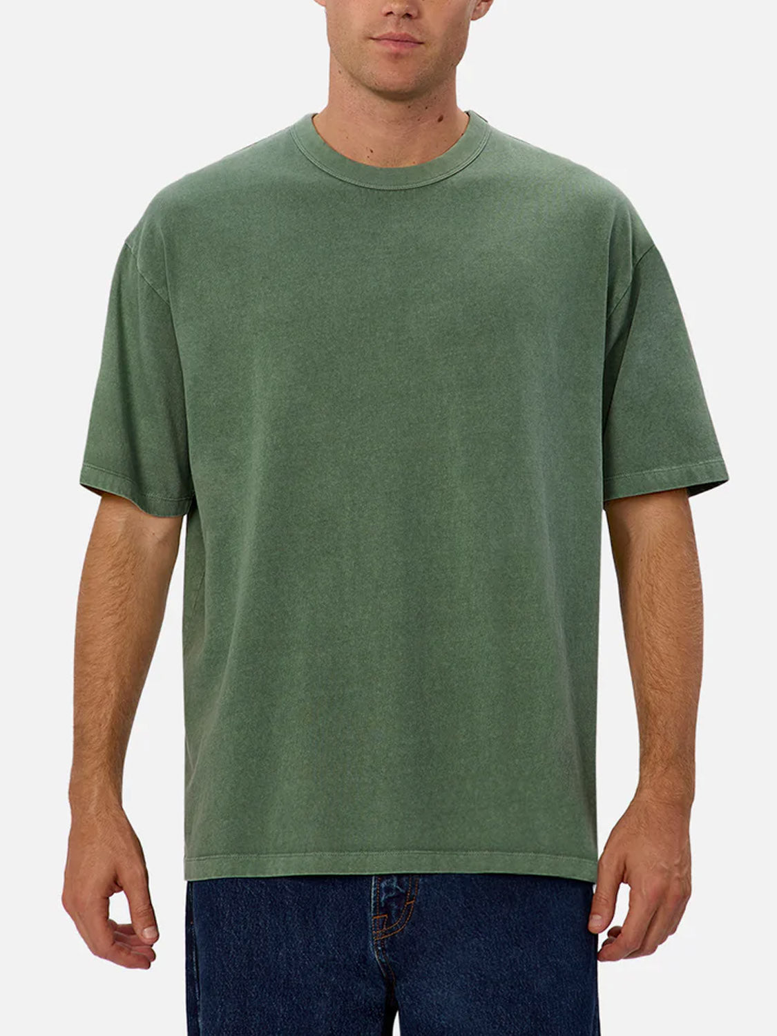 A man wearing The Del Sur Tee by Industrie—a relaxed fit, short-sleeved olive green 100% cotton t-shirt—and blue jeans stands facing forward against a plain white background. His face is partially visible.