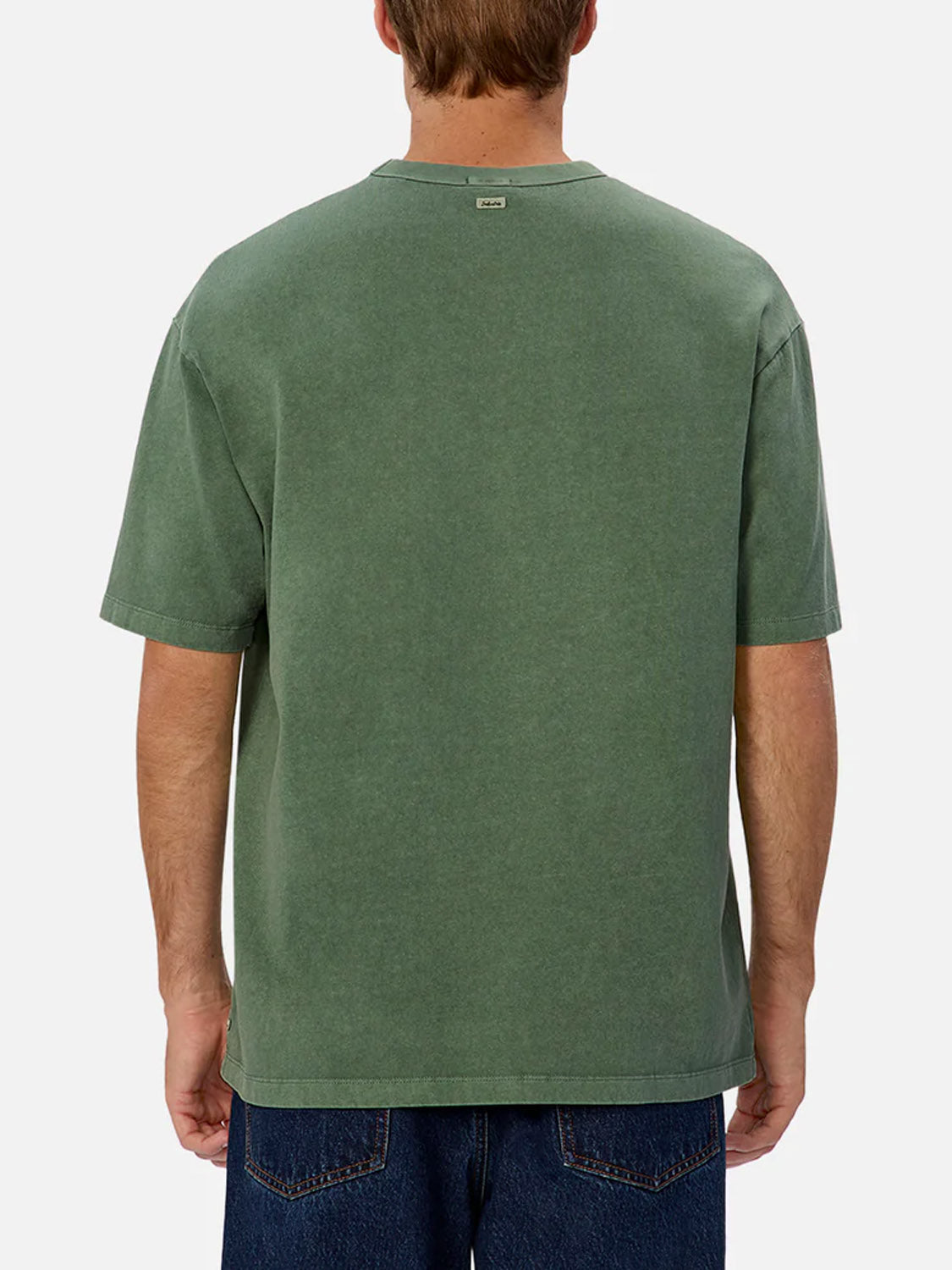 A person is seen from behind wearing Industrie’s The Del Sur Tee, a relaxed fit, 100% cotton green crew neck t-shirt with a small tag near the neckline, paired with blue jeans against a plain light background.