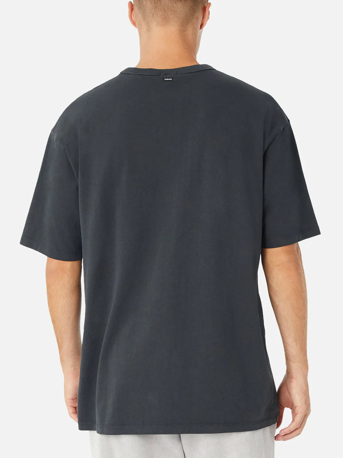 A person is shown from the back wearing the Industrie Del Mar Boxy T-Shirt in dark gray with light-colored shorts, set against a plain white background.