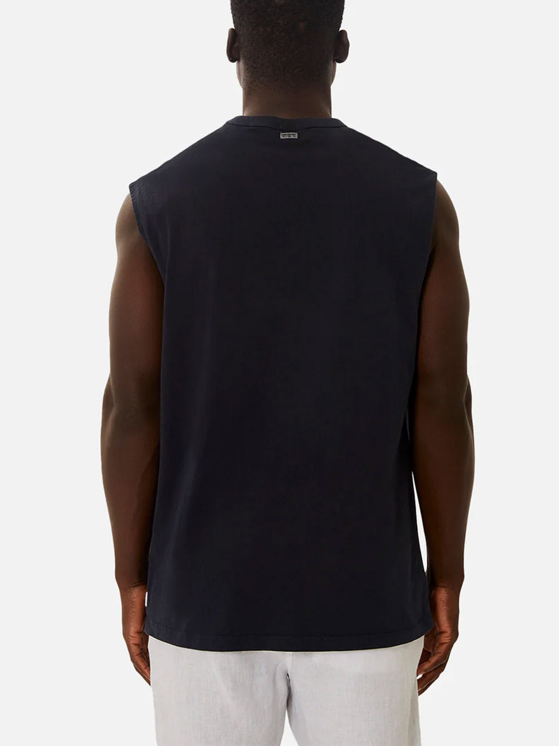 A man is seen from behind wearing the Industrie Del Sur Sleeveless T-Shirt and light gray shorts, standing against a plain light background.